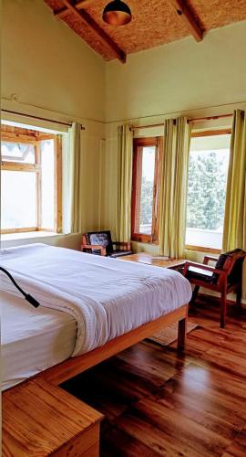 a large bed in a room with two windows at Chirping Orchard, Mukteshwar in Mukteswar