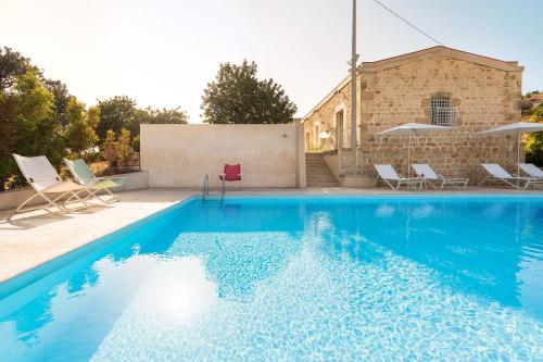 Una piscina con sillas y un edificio. en Villa Luna, en Scicli