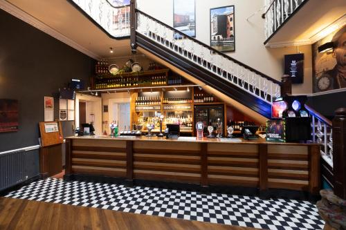 a bar in a pub with a staircase at The Mount by Greene King Inns in Wigan