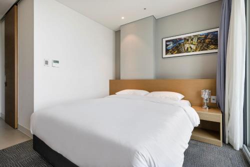 a bedroom with a large white bed and a window at Marysol by Haeundae beach in Busan