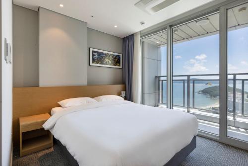 a bedroom with a large bed and a large window at Marysol by Haeundae beach in Busan