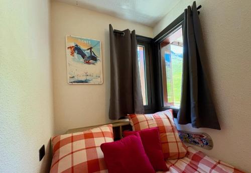 een slaapkamer met een bed met rode kussens en een raam bij RPP C213 - Charmant appt 4pers-Ski aux pieds in Tignes