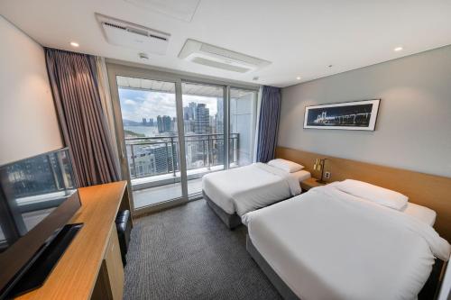 a hotel room with two beds and a large window at Marysol by Haeundae beach in Busan