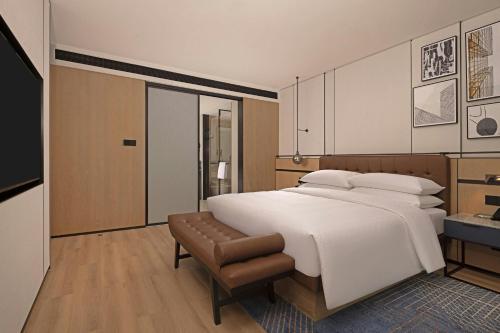 a bedroom with a large white bed and a chair at Four Points by Sheraton Mianyang in Mianyang