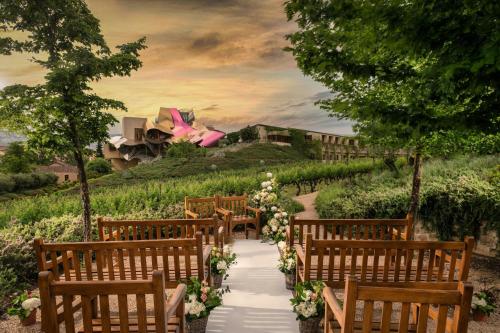 a row of benches with a aisle with flowers at Hotel Marqués de Riscal, a Luxury Collection Hotel, Elciego in Elciego