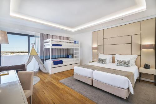 a bedroom with a large bed and a living room at Jupiter Albufeira Hotel - Family & Fun - All Inclusive 24h in Albufeira
