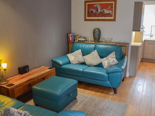 Una sala de estar con un sofá azul y una silla. en Beach Comber Cottage, en Marazion