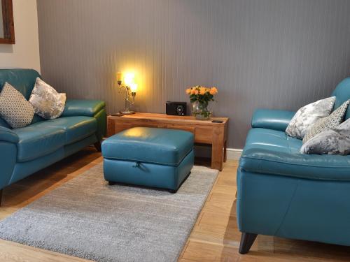 Una sala de estar con dos sofás azules y una mesa. en Beach Comber Cottage, en Marazion