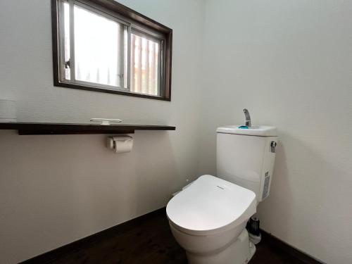 a bathroom with a white toilet and a window at 別荘五岳 in Minami Aso