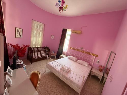 a pink bedroom with a bed and a crib at Tower Traditional Pool Villa in Kremasti