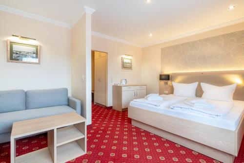 a bedroom with a large bed and a blue couch at Hotel am Gothensee in Heringsdorf