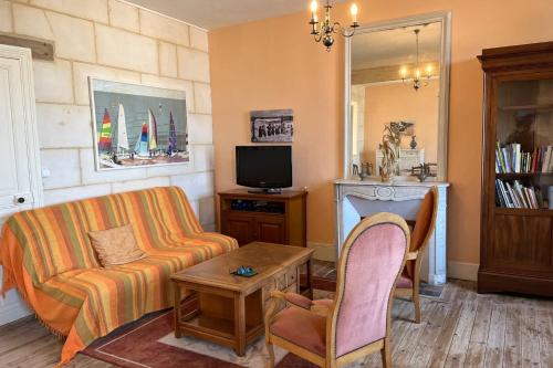 un salon avec un canapé et une télévision dans l'établissement Spacious 19th century house, à Saint-Aubin-sur-Mer
