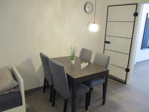 a dining room table with chairs and a clock on the wall at Parsberger City Rooms 104 in Parsberg