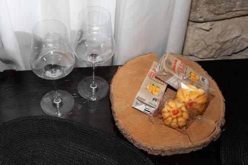 two wine glasses and a plate of food on a table at Ξενώνας Πελασγός in Sparti