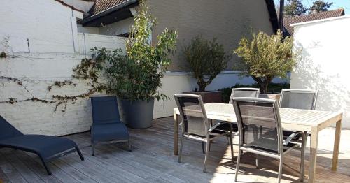 une table et des chaises en bois sur une terrasse dans l'établissement Large house terrace entrance Le Touquet, à Cucq