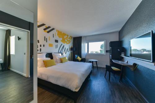 a hotel room with a bed and a desk at Golden Tulip Roissy Saint Witz in Saint-Witz