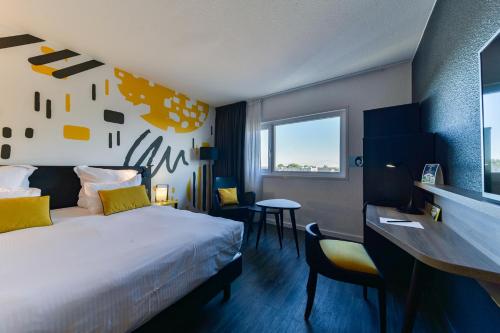 a hotel room with a bed and a desk at Golden Tulip Roissy Saint Witz in Saint-Witz