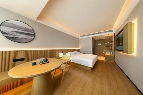 a hotel room with a bed and a table at Floral Hotel Banlan Cangzhou Convention and Exhibition Center High-speed Railway West Station in Zhifangtou