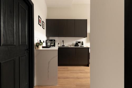 a kitchen with black cabinets and a white counter top at Moment Blythswood St in Glasgow