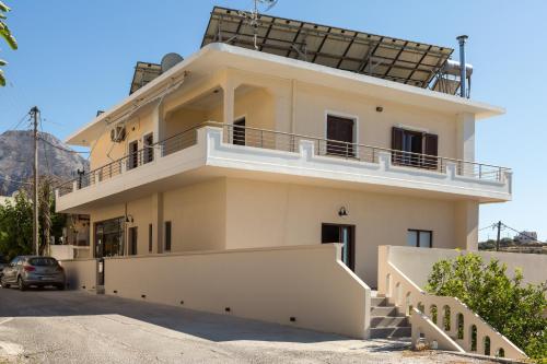 a white house with a balcony on top of it at Fyllianos Apartments in Plátanos