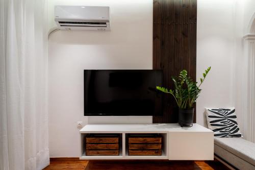 a tv on a white stand in a living room at Magnus Apollo in Thessaloniki