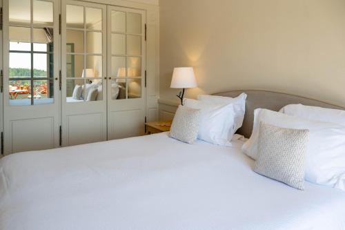 a bedroom with a white bed with white pillows at L'Hôtel & Spa du Castellet in Le Castellet