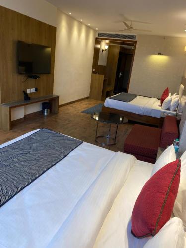 a hotel room with two beds and a flat screen tv at Hotel Wedcaton By Tivoli - Ambala in Ambāla