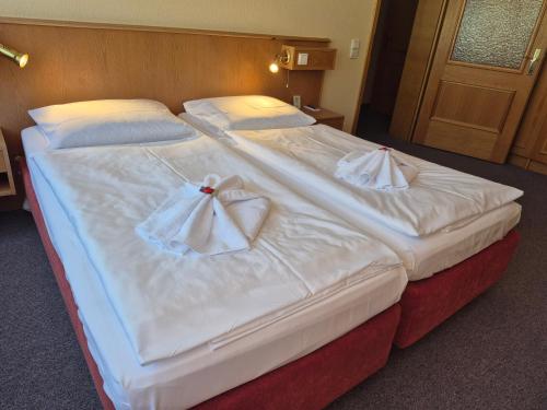 two beds in a hotel room with white sheets at Panorama Hotel Oberwiesenthal in Kurort Oberwiesenthal