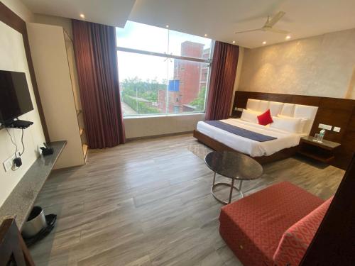 a hotel room with a bed and a large window at Hotel Wedcaton By Tivoli - Ambala in Ambāla