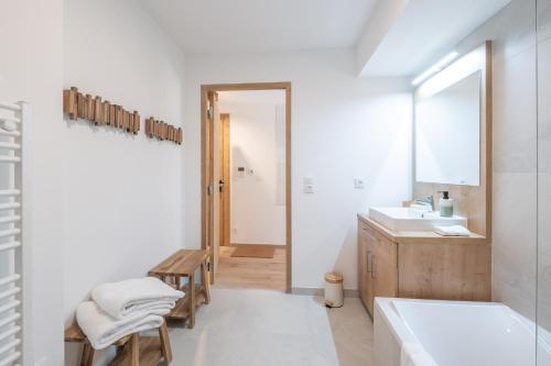 a white bathroom with a tub and a sink at Le Refuge du Pic in L'Alpe-d'Huez