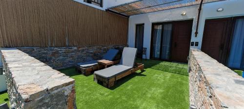 a patio with a couch and a chair and grass at Rigas Hotel Skopelos in Skopelos Town