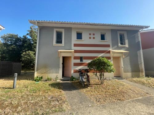 une maison avec un vélo garé devant dans l'établissement Rêves d'Océan villa familiale calme bord de mer piscine partagée surf, à Soulac-sur-Mer