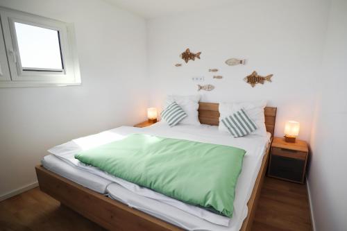 トッセンスにあるWatt n` Kokolores - Ferienhaus mit Terrasse und Infrarotsaunaのベッドルーム1室(大型ベッド1台、緑のシーツ付)