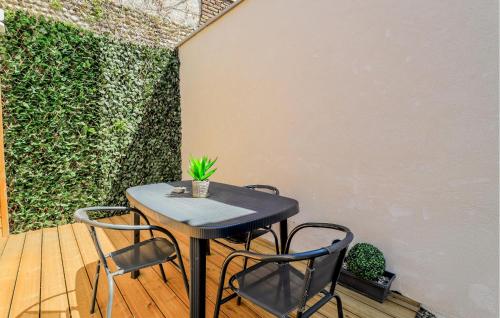 a table and chairs on a patio with a green wall at Jolie Maison Proche Plage in Le Crotoy