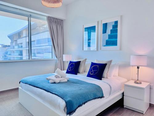 a white bedroom with a large bed with blue pillows at Stylish 1BR in Mayan, Yas Island in Abu Dhabi
