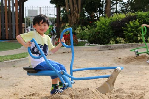 a young boy sitting on a swing in a sandbox at Hong Kong Gold Coast Hotel in Hong Kong