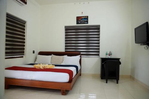 a bedroom with a bed and a flat screen tv at Athirappilly Ambady Resort in Athirappilly
