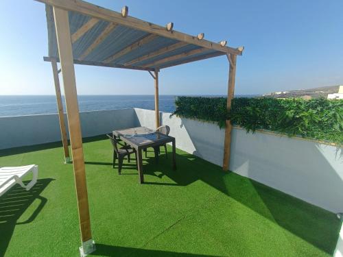 a table and chairs under a pergola on a balcony at Studio avec terrasse et vue mer in El Escobonal