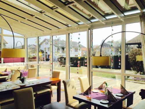 a dining room with tables and chairs and large windows at Hotel-Restaurant Bellevue in Ruhpolding