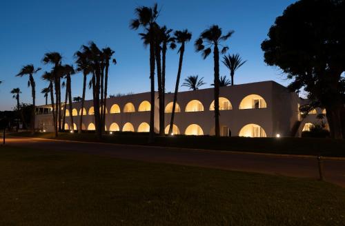 a building with palm trees in front of it at AluaSoul Menorca - Adults Only in S'Algar