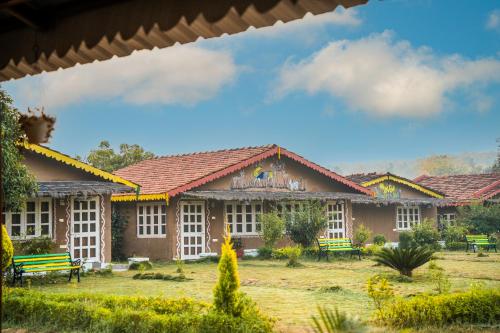 a group of buildings with benches in a yard at WOW STAYZ2 Pachmarhi Foothill Cottages in Pachmarhī