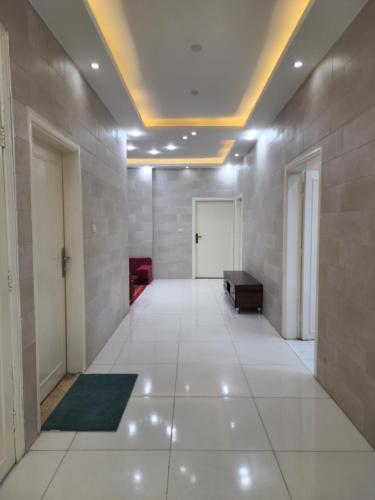 a large room with a hallway with white floors and a door at Monani in Amman