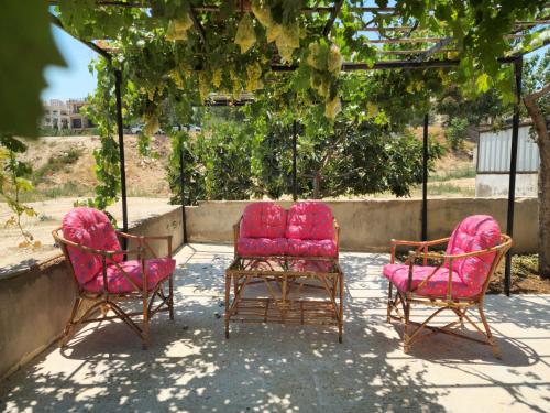 three chairs with pink cushions sitting on a patio at Monani in Amman