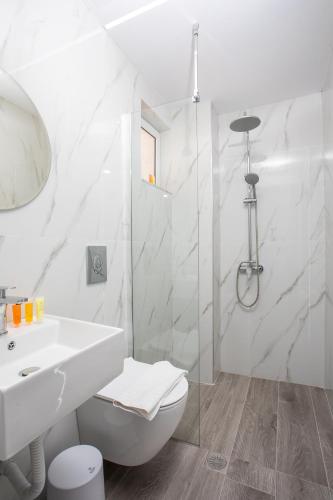 a white bathroom with a sink and a toilet at Vickys Rooms - Faliraki in Faliraki