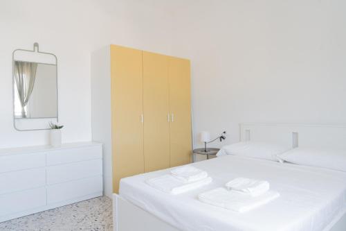 a white bedroom with two white beds and a cabinet at Stadium Residence in Brescia