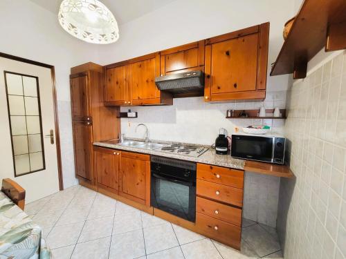 a kitchen with wooden cabinets and a sink and a microwave at Appartamento Galileo Ferraris, in Vercelli