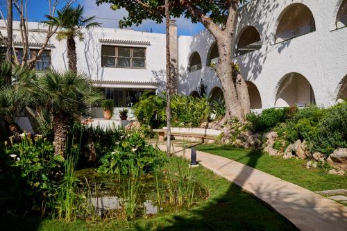 a garden in front of a building with trees and plants at AluaSoul Menorca - Adults Only in S'Algar