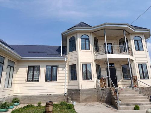 a large white house with a porch and stairs at Guest House Bektash in Kyzart