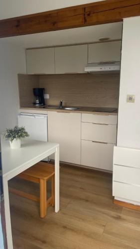 a kitchen with white cabinets and a white table at La Tuile Aux Loups in Corps