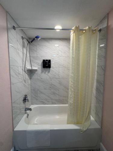 a white bath tub with a shower curtain in a bathroom at Atlantic Shores Motel in Daytona Beach